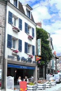 un edificio con persianas azules en una calle de la ciudad en Hotel Le Chapitre en Aubusson
