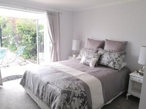 a white bedroom with a large bed and a sliding glass door at Terra Nostra in Mapua
