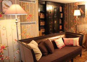 a couch with pillows in a living room with a lamp at Hôtel du Romancier in Paris