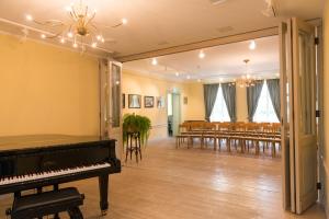 a room with a piano and tables and chairs at Loona Manor Guesthouse in Kihelkonna