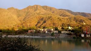 a view of a lake with mountains in the background at Sanidhya Inn in Rishīkesh