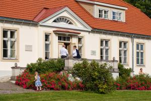 Loona Manor Guesthouse في Kihelkonna: مجموعة من الناس تقف خارج المنزل