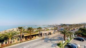 een stadsstraat met palmbomen en een strand bij Residence Colibrì Family & Bike in Loano