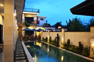 a house with a swimming pool in front of a house at Tirtha Canggu Suites in Canggu