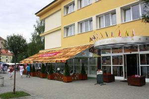 a yellow building with people walking in front of it at Arkada Hotel in Bučovice
