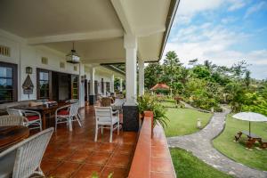 um pátio exterior com mesas e cadeiras e um jardim em Bukit Asri Lodge em Seraya