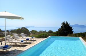 uma piscina com cadeiras e um guarda-sol em Urania Luxury Villas em Vasiliki