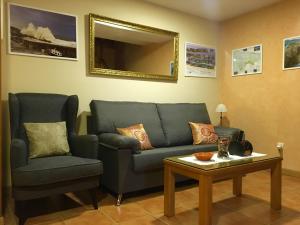 a living room with a couch and a chair and a table at Apartamentos El Pradón de Santa Marina in Parres de Llanes