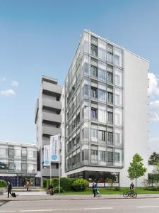 un grand bâtiment blanc dans une rue de la ville dans l'établissement apartmenthaus international, à Munich