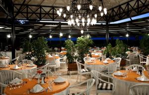een eetkamer met tafels en witte stoelen en een kroonluchter bij Sunrise Resort Hotel in Kizilagac