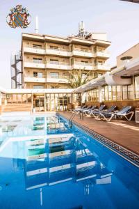 un hôtel avec une piscine en face d'un bâtiment dans l'établissement Hotel Victoria, à Segur de Calafell