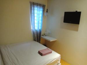 a small room with a bed and a television at Hotel 77 Rawang in Rawang