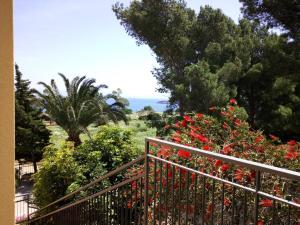 サン・ヴィート・ロ・カーポにあるCasa Ciclaminoの赤い花と木々と海の景色を望むバルコニー