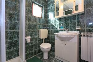 a green tiled bathroom with a toilet and a sink at Villa Barbara in Vrlika