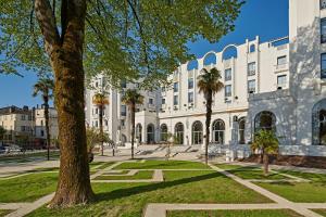 ダクスにあるHotel & Spa Vacances Bleues Le Splendidのヤシの木が前に立つ大きな白い建物