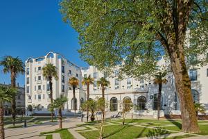 un gran edificio blanco con palmeras delante en Hotel & Spa Vacances Bleues Le Splendid, en Dax