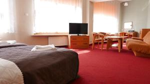 a hotel room with two beds and a television at Ośrodek Szkoleniowo - Wypoczynkowy Guzianka in Ruciane-Nida