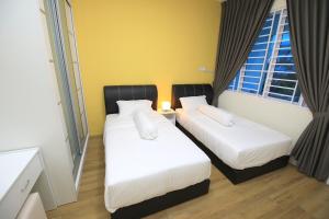 2 Betten in einem Zimmer mit 2 Fenstern in der Unterkunft 722 Homestay in Kuching