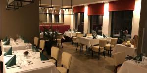 uma sala de jantar com mesas e cadeiras brancas em Hotel Allegro em Halberstadt
