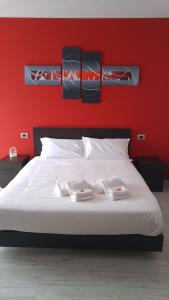 ein Schlafzimmer mit einem weißen Bett und einer roten Wand in der Unterkunft Millaenya Inn in Entratico