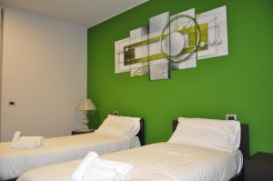 2 Betten in einem Zimmer mit grüner Wand in der Unterkunft Millaenya Inn in Entratico