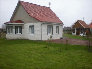 una casa blanca con techo rojo en un patio en Résidence André, en Quend