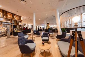 a salon with blue chairs and tables and a woman at JUFA Hotel Hamburg HafenCity in Hamburg