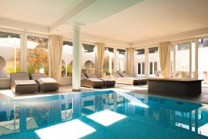 ein großer Pool mit Sofas und Stühlen in einem Haus in der Unterkunft Naturresort & Spa Schindelbruch in Stolberg i. Harz