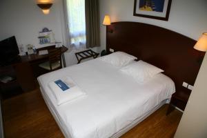 a bedroom with a large white bed and a desk at Kyriad Chateauroux in Châteauroux
