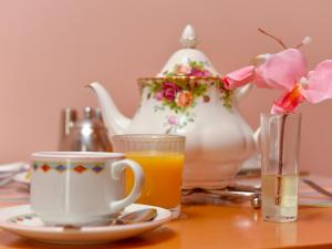 uma mesa com uma chávena de sumo de laranja e um bule de chá em The Warren Guest House em Carlisle