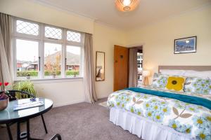 但尼丁的住宿－Sunny Mornington 2 Bedroom Guest Suite，卧室配有床、桌子和窗户。