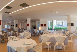 salę bankietową z białymi stołami i krzesłami w obiekcie Futura Club Spiagge Bianche w mieście Fontane Bianche