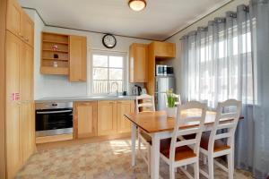 a kitchen with a table and chairs and a clock at Kasekese Holiday Home with Sauna and Garden in Kuressaare