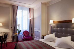 a hotel room with a bed, chair, and nightstand at Hotel Schweizerhof Zürich in Zurich