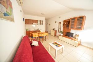 un soggiorno con divano rosso e una cucina di Apartments Katoro Relax a Umag (Umago)