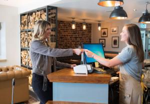 twee vrouwen die handen schudden aan een balie in een koffiehuis bij Lodge at Solent in Fareham