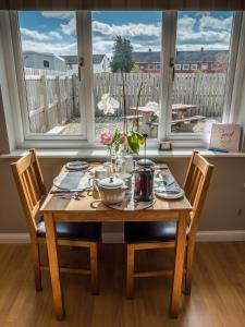 a dining room table with chairs and a table and a window at The Birches in Dingwall