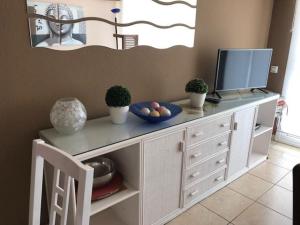 a white cabinet with a television and a bowl of fruit on it at Arogran II in Platja d'Aro