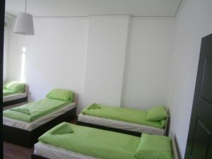 two beds in a room with green sheets at Ivory Tower Hostel in Sofia