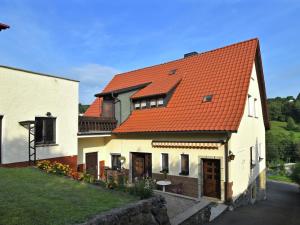 ein großes weißes Haus mit orangefarbenem Dach in der Unterkunft Lovely holiday home in the Thuringian Forest with roof terrace and great view in Bad Liebenstein