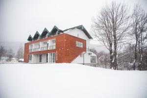a red brick building in the snow with trees at Hotel Serdar in Mojkovac