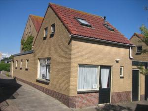 une maison en briques avec un toit rouge dans l'établissement Duinnachtegaal, à Egmond aan Zee