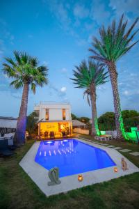 a swimming pool with palm trees in front of a house at Destina Hotel in Cesme