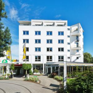 リューネンにあるRinghotel Am Stadtparkの白いホテルで、目の前にロータリーがあります。