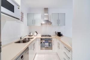 a white kitchen with white cabinets and a sink at York Apartments on Grenfell in Adelaide