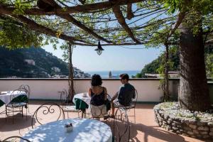 Ein Mann und eine Frau sitzen an einem Tisch auf einer Terrasse in der Unterkunft Hotel Villa Annalara charme and Relax in Amalfi