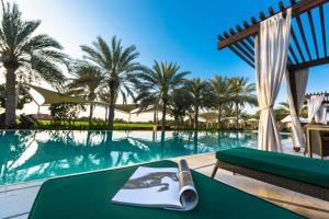 un libro su un tavolo accanto alla piscina di Meliá Desert Palm Member of Meliá Collection a Dubai