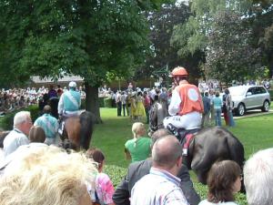una multitud de personas viendo a dos hombres montando caballos en Leuchtners an der Rennbahn, en Iffezheim