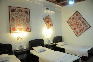 Zimmer mit 3 Betten und Wandgemälde in der Unterkunft Al Bukhari Boutique Hotel in Buxoro