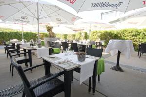 ein Restaurant mit weißen Tischen, Stühlen und Sonnenschirmen in der Unterkunft Hotel Dampfmühle in Neukirchen-Vluyn